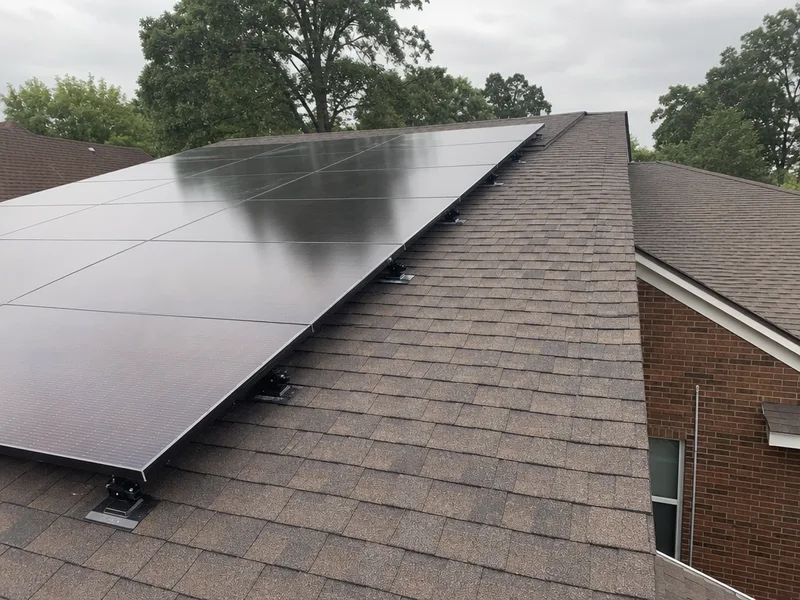 Rows of solar modules on rail mounts across a residential shingle roof, with an empty access strip left along the ridge